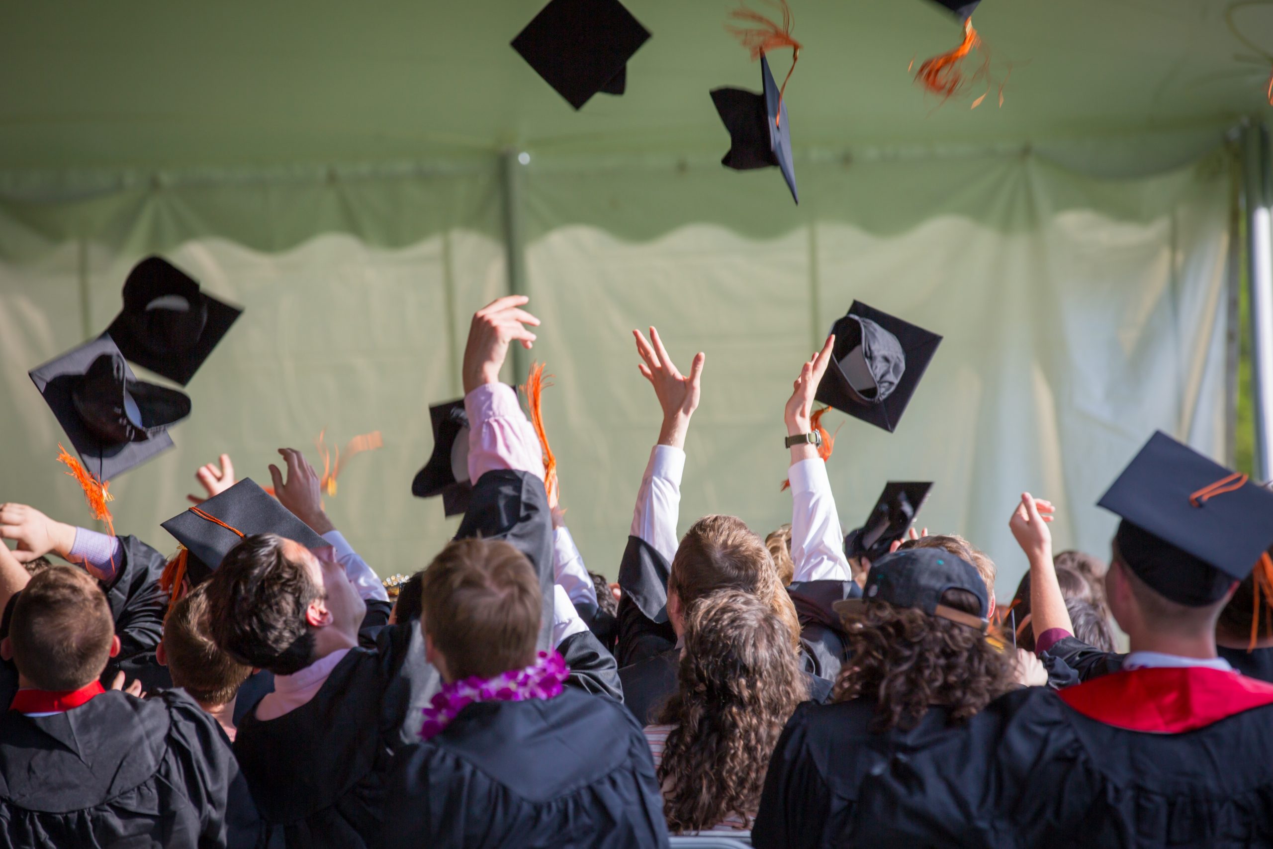 students tossing graduation caps