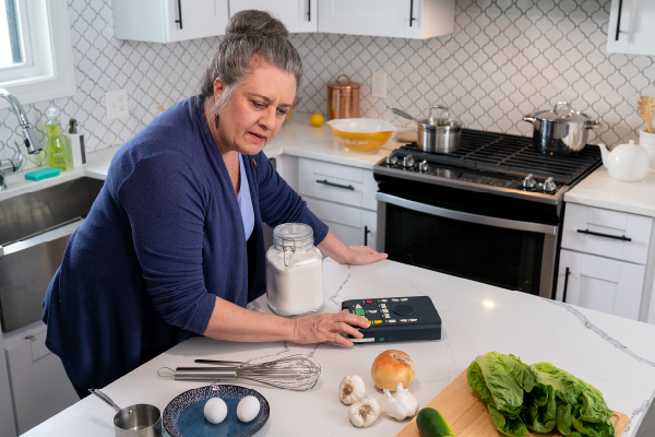visually impaired woman using a reading machine to prepare a meal in the kitchen