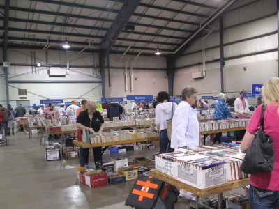 People looking through table of books during book sale.